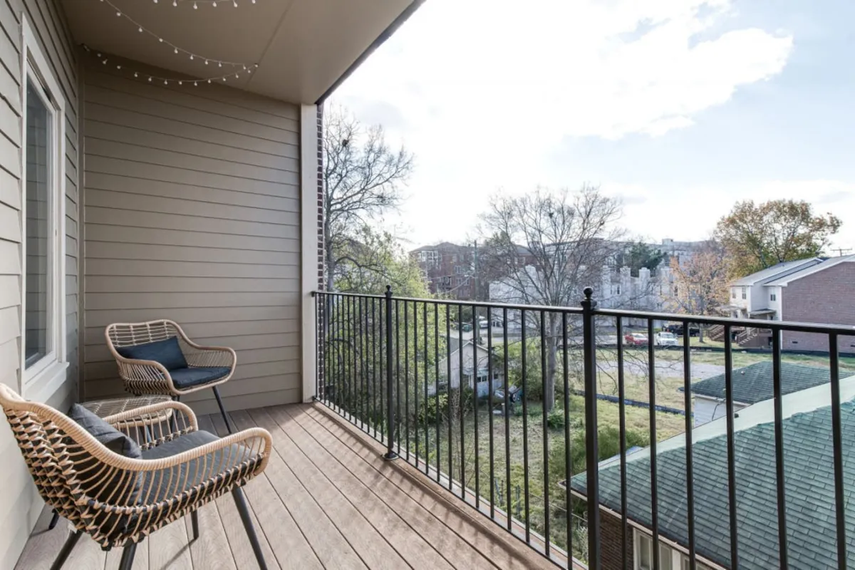 The hero image showcases the condo's private balcony at sunset, featuring inviting woven chairs, soft string lights, and a peaceful ambiance perfect for relaxing or dining outdoors. The setting captures the tranquil vibe of the space, with hints of city life in the background and a warm, welcoming glow that invites guests to unwind.