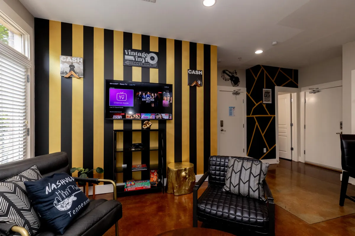 A contemporary living/dining area with a striped accent wall, a Smart TV positioned for easy viewing, plush seating, and decorative accents. The area feels vibrant and perfect for watching movies or enjoying lively get-togethers, echoing the social, entertainment-focused atmosphere mentioned in the section.